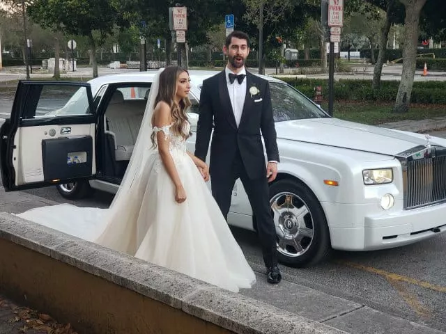 groom and bride standing out of pearl white rolls royce phantom wedding car on wedding day.