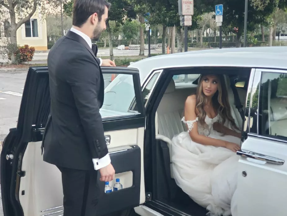 groom and bride getting out of pearl white rolls royce phantom wedding car on wedding day.